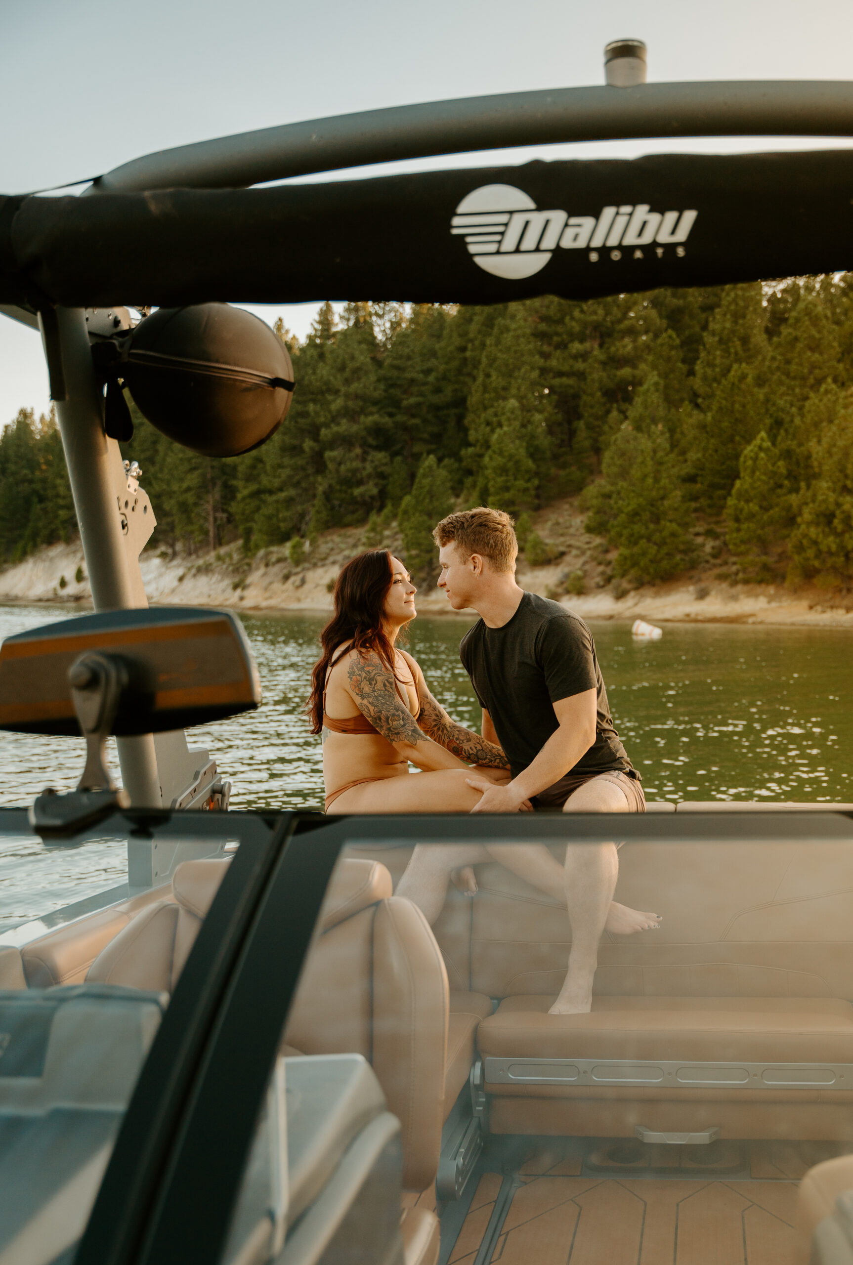 Couple snuggled up on the back of the boat for a sunset summer engagement photo session.