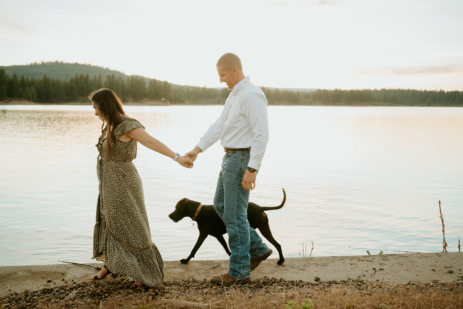 Wedding Photographers Reno capture couple holding hands while walking along lake with dog