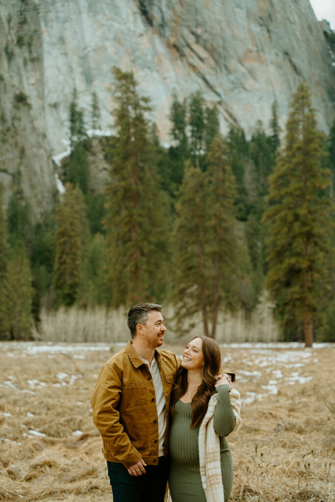Yosemite wedding photographer captures couple standing together while woman looks up at husband during maternity photos