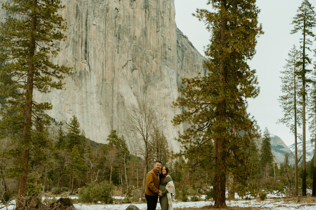 Yosemite wedding photographer captures expectant parents embracing in Yosemite National Park celebrating upcoming baby's arrival