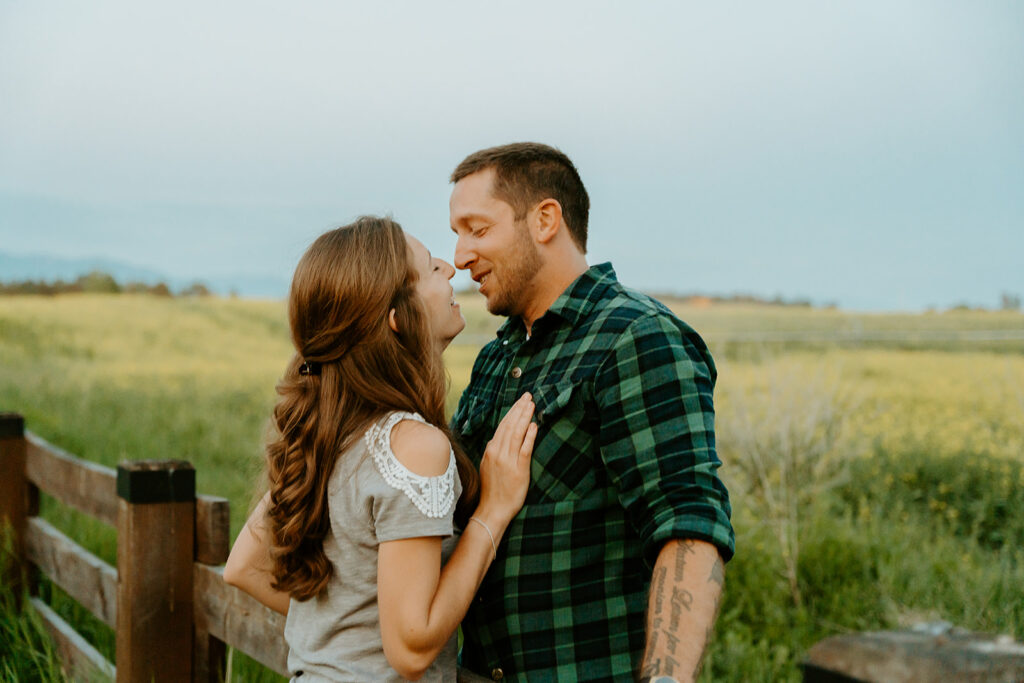 Reno wedding photographer captures man leaning against fence as woman looks up to kiss him