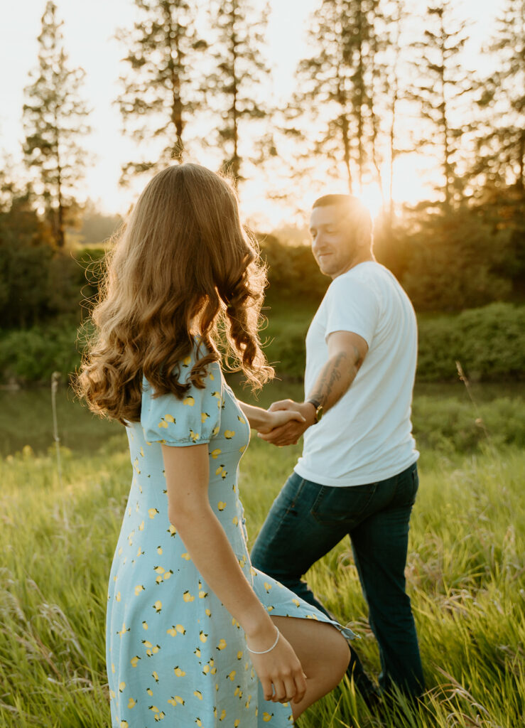 Reno wedding photographer captures man and woman walking together through field of green grass during spring engagement photos