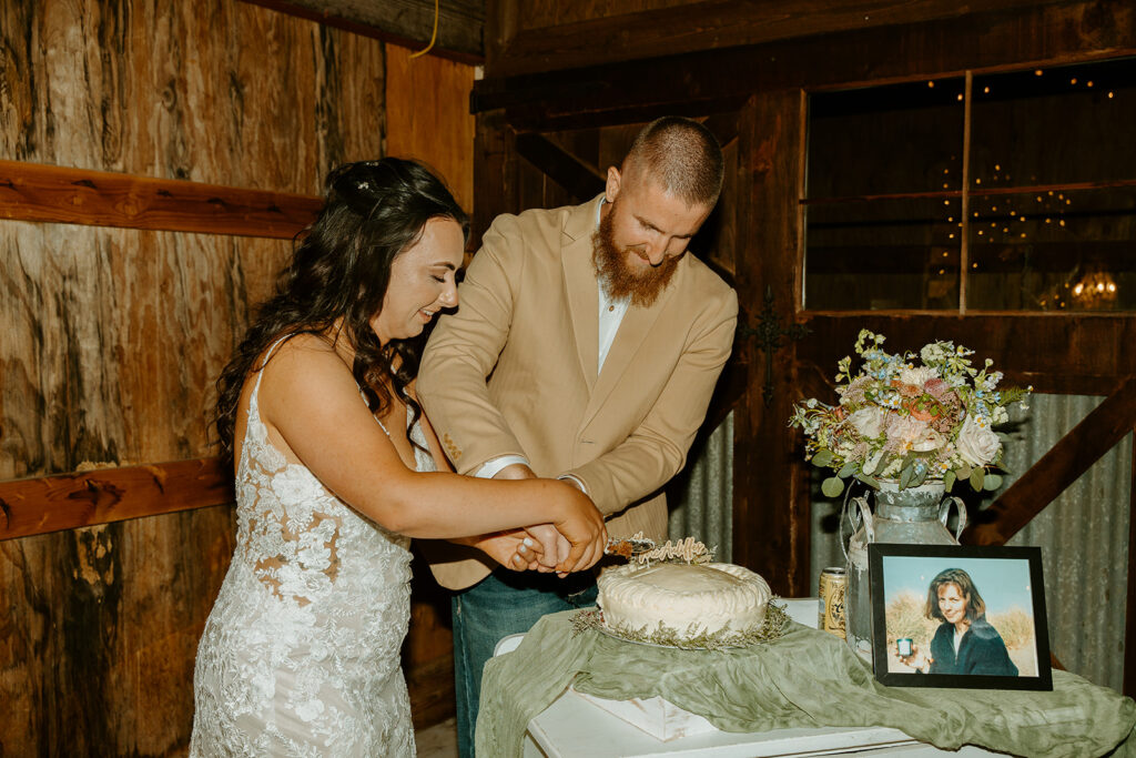 Reno Wedding Photographer captures bride and groom cutting cake with framed photos of loved ones around to honor them