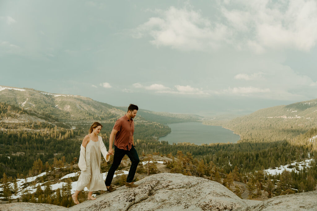 Reno wedding photographer captures newly engaged couple walking hand in hand across boulder during spring engagement photos