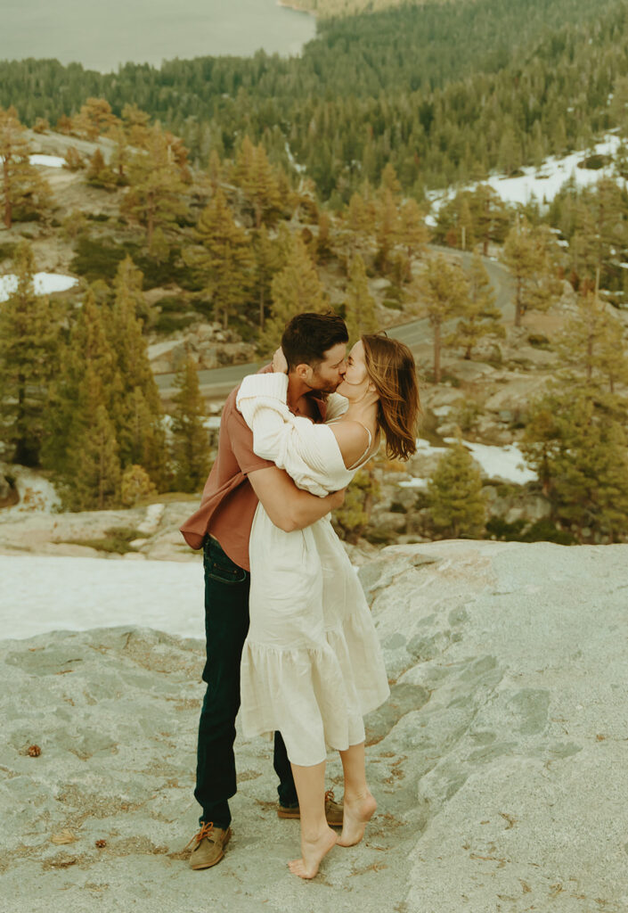Reno wedding photographer captures couple hugging and kissing on boulder during spring engagement photos