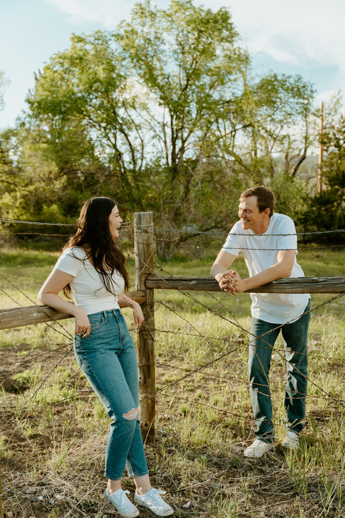 Reno wedding photographer captures couple leaning against fence during summer engagement photos