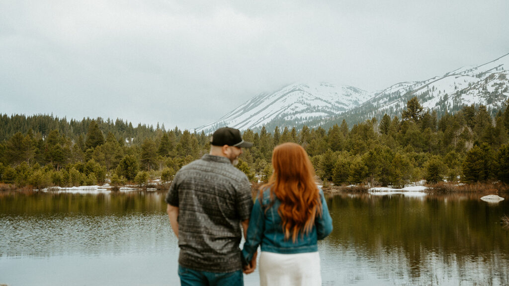 Reno wedding photographer captures newly engaged couple looking at mountains together while holding hands