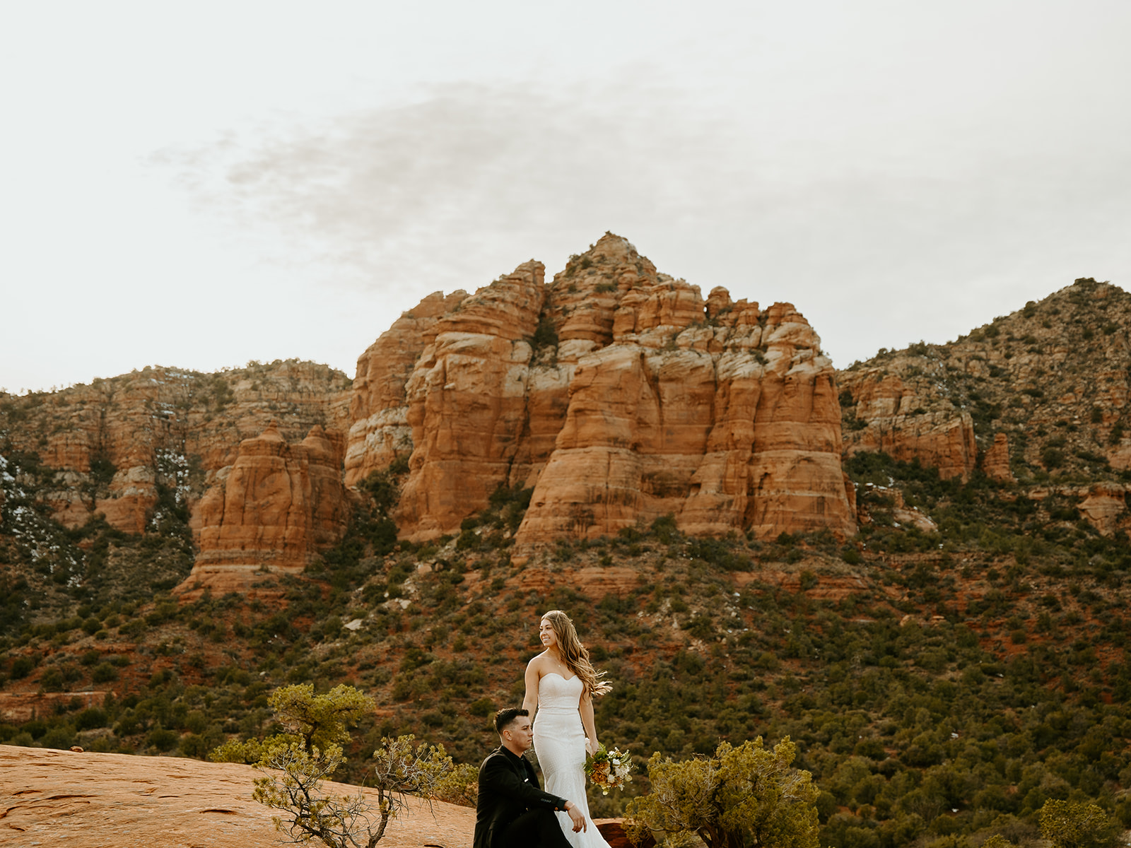 Wedding Photographers Reno capture bride and groom standing together on red rock in Arizona during adventure elopement