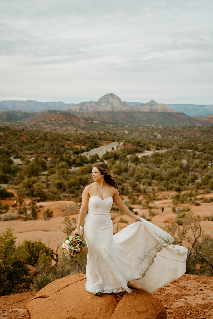 Wedding Photographers Reno capture bride holding train while wind blows on top of mountain