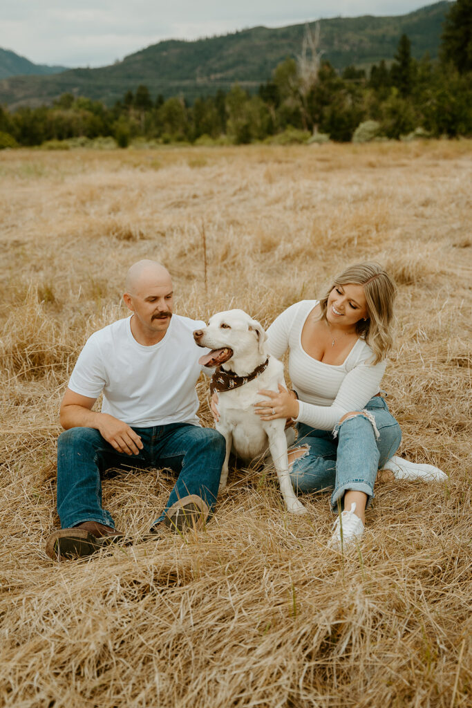 Reno Wedding Photographer captures newly engaged couple sitting on grass with dog